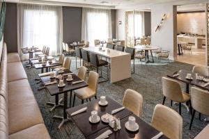 a restaurant with tables and chairs and windows at DoubleTree by Hilton Boston Logan Airport Chelsea in Chelsea