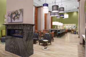 a waiting room with a fireplace and a restaurant at Hampton Inn & Suites Syracuse North Airport Area in North Syracuse