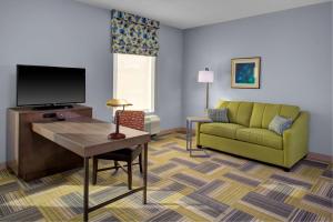a living room with a couch and a tv at Hampton Inn & Suites Syracuse North Airport Area in North Syracuse
