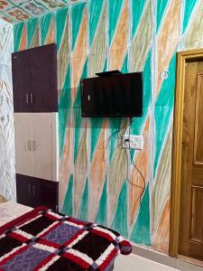 een slaapkamer met een kleurrijke muur en een tv. bij Hotel Maheshwari & Banquet Hall in Chamba