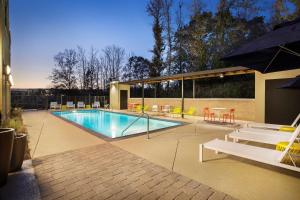 a swimming pool with tables and chairs and an umbrella at Home2 Suites By Hilton Oxford in Oxford