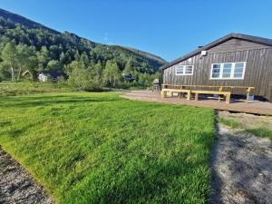 eine Bank im Gras vor einem Gebäude in der Unterkunft Tangen - cabin with 4 bedrooms - great nature in Norheimsund