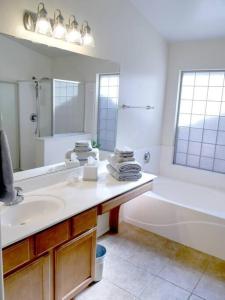 a white bathroom with a sink and a tub and a tubermott at Everything New! Ball Park Oasis With Heated Pool in Goodyear