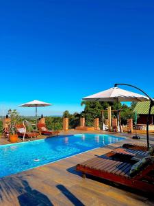 a swimming pool with chairs and umbrellas at Águas Chalés Temporada - Chalés e Lofts Confortáveis - Piscina - Próximo ao Thermas in Águas de São Pedro