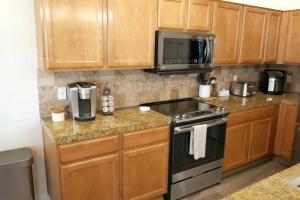 a kitchen with wooden cabinets and a stove and microwave at Everything New! Ball Park Oasis With Heated Pool in Goodyear