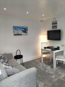 a living room with a couch and a table and a tv at Sea Shells in Torquay