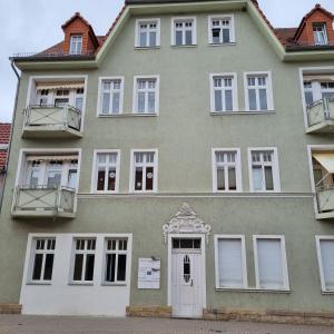 un gran edificio verde con puertas y ventanas blancas en Ferienwohnung "An der Querne" Querfurt, en Querfurt