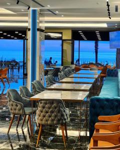 um restaurante com mesas e cadeiras com o oceano ao fundo em Hotel LEON - Beach Front em Shëngjin