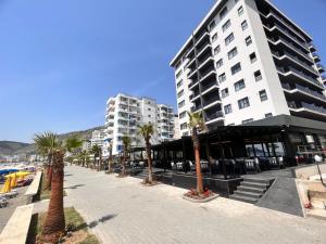 una calle con palmeras frente a un edificio en Hotel LEON - Beach Front en Shëngjin