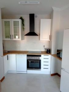 a kitchen with white cabinets and a stove top oven at Apartamento Vistas a ensenada in Meaño
