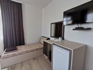 a hotel room with a couch and a desk and a tv at Вила Дъбрава in Sinemorets