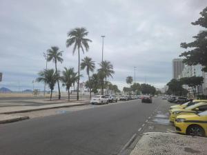 uma rua com carros estacionados e palmeiras numa praia em Suhcasa Leme Beach 3 quartos no Rio de Janeiro