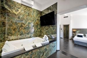 a bathroom with a tub and a bed and a television at Hotel POZZO DI BORGO in Ajaccio