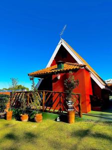 a red house with plants inront of it at Águas Chalés Temporada - Chalés e Lofts Confortáveis - Piscina - Próximo ao Thermas in Águas de São Pedro