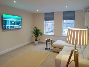 a living room with a couch and a flat screen tv at Executive Barchester House Apartment in Salisbury