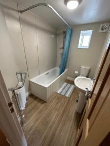 a bathroom with a tub and a toilet and a sink at Executive Barchester House Apartment in Salisbury