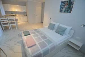 a white bedroom with a bed and a kitchen at APARTAMENTY POD ŻAGLAMI MIELENKO in Mielenko