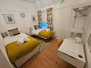 ein kleines Schlafzimmer mit 2 Betten und einem Tisch in der Unterkunft Stylish 2 Bed Apt - Harry Potter/ Leavesden Studios/Watford/Hemel Hempstead - Families/Professionals & Contractors Welcome - Serviced Accomodation in Sarratt