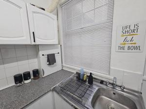 een keuken met een wastafel en een raam met een bord bij Stylish 2 Bed Apt - Harry Potter/ Leavesden Studios/Watford/Hemel Hempstead - Families/Professionals & Contractors Welcome - Serviced Accomodation in Sarratt