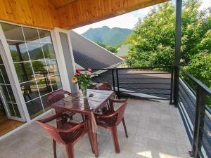a wooden table and chairs on a patio with a view at Qafqaz Flower Villa in Gabala