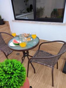 a table with two chairs and two glasses of orange juice at JB House in Nazaré