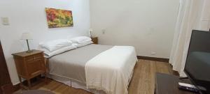 a bedroom with a white bed and a tv at Hotel Yacanto in Yacanto