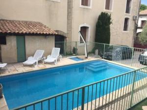 uma piscina com duas cadeiras brancas ao lado de um edifício em Villa Nova Raï du Mas des Fontaines - Jardin, piscine, terrasses 4 à 6 pers em Montagnac