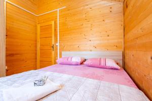 Cama en habitación de madera con 2 almohadas en KATANA VILLAGE APARTMENT, en Ulcinj