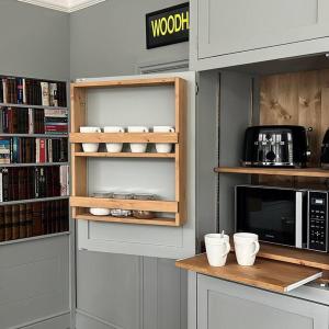 a kitchen with a shelf with cups and a microwave at Glenesk No 1 , Woodhall Spa in Lincolnshire