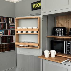 a kitchen with a shelf with cups and a microwave at Glenesk No 1 , Woodhall Spa in Woodhall Spa