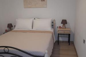 a bedroom with a white bed and a nightstand with two lamps at 4 Season Cozy Home in Samothraki