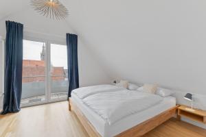 a white bedroom with a bed and a large window at Design-Apartment - Küche - Balkon - Tiefgarage in Leinfelden-Echterdingen