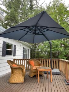 una sombrilla negra en una terraza con sillas y mesa en Tantallon Guest Room with Private Beach, en French Village