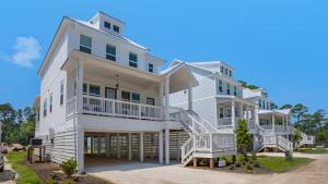 une grande maison blanche avec des escaliers en face de celle-ci dans l'établissement Sitting Bayside, à Santa Rosa Beach