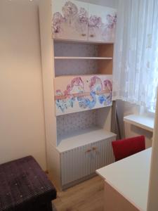 ein Zimmer mit einem Regal und einem roten Stuhl in der Unterkunft M2 Art in Giżycko