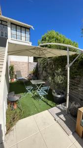 a patio with a table and chairs under an umbrella at Appartement verrière à deux pas des plages… in Hyères