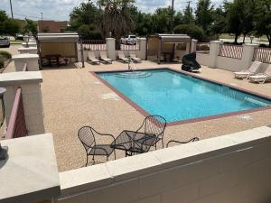 a swimming pool with two chairs and a table at Budget Host Inn and Suites Cameron in Cameron