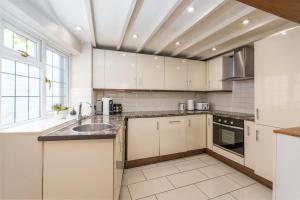 a kitchen with white cabinets and a sink at Bard's Cottage in Alcester