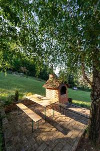 a picnic table sitting under a tree with a brick oven at Fruska Pool House in Sremska Kamenica