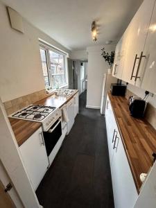La cuisine est équipée de placards blancs et d'un four avec plaques de cuisson. dans l'établissement Perfect Home From Home In Stoke on Trent, à Etruria