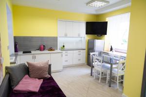 a kitchen with yellow walls and white cabinets and a table at Apartament przy Rynku in Ostrowiec Świętokrzyski