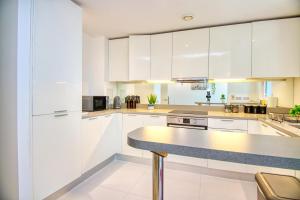 a kitchen with white cabinets and a counter top at Your gateway to London & Heathrow, Stylish flat near station in Hayes