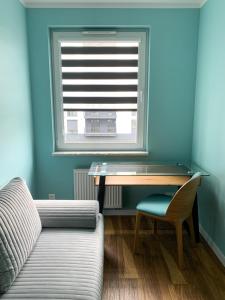 a room with a desk and a couch and a window at Belzacka City Apartment in Piotrków Trybunalski