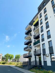 een wit appartementencomplex met balkons in een straat bij Belzacka City Apartment in Piotrków Trybunalski