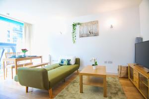sala de estar con sofá verde y TV en Your gateway to London & Heathrow, Stylish flat near station en Hayes