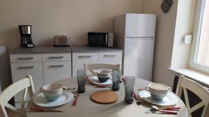 eine Küche mit einem weißen Tisch mit zwei Tassen und Stühlen in der Unterkunft Appartement Fx 1 in Saint Die