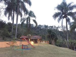 una casa con un parque infantil con palmeras en Recanto Vista Mantiqueira en Guararema