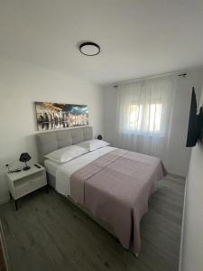 a white bedroom with a large bed and a window at NeRi in Trogir