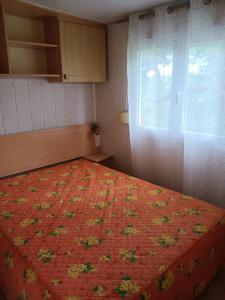 sypialnia z łóżkiem z pomarańczową kołdrą i oknem w obiekcie En Saubis 