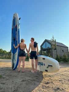 dos personas sosteniendo sus tablas de surf en la playa en Jabłonka Resort, en Jabłonka